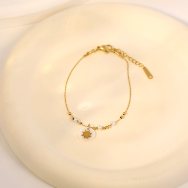 Großhändler Eclat Paris - Goldenes Perlenarmband und goldene Perlen mit Sonnenanhänger auf Perlmutt